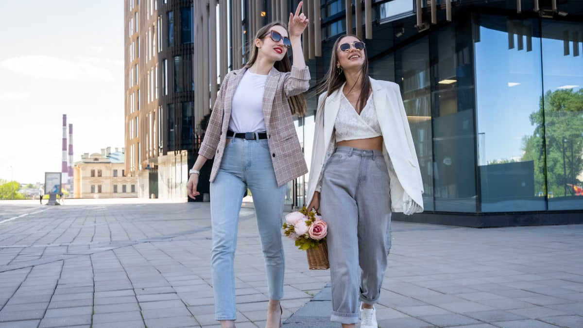 Two stylish women in sunglasses walking outdoors, embracing fashion trends.